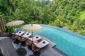 View of the swimming pool water and sunbeds in the tropical jungle near Ubud, Bali, Indonesia , top view