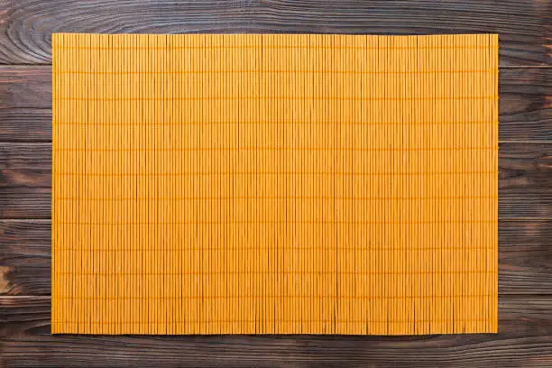 Empty Asian Food Background. Yellow Bamboo mat on wooden background top view with copy space flat lay.