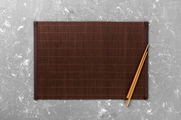 istock two sushi chopsticks with empty bamboo mat or wood plate on cement Background Top view with copy space. empty asian food background 1162351096