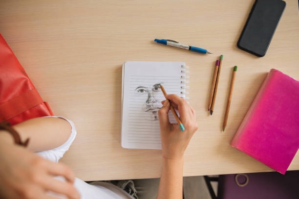 Artistic girl drawing a face on a note pad