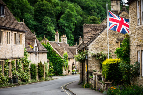 traditioneel idyllisch engels landelijk dorp met gezellige huisjes en britse vlag - cotswold stockfoto's en -beelden