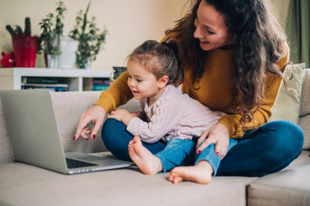 istock Mother and daughter using laptop on sofa 1162354539