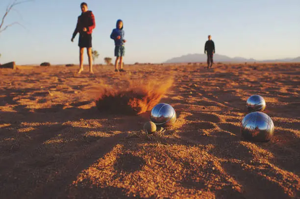 Pétanque Boules Game being played by three boys in the desert at sunrise Namib Rand Namibia Africa