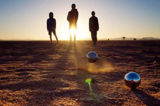 Pétanque Boules Game being played by three boys in the desert at sunrise Namib Rand Namibia Africa