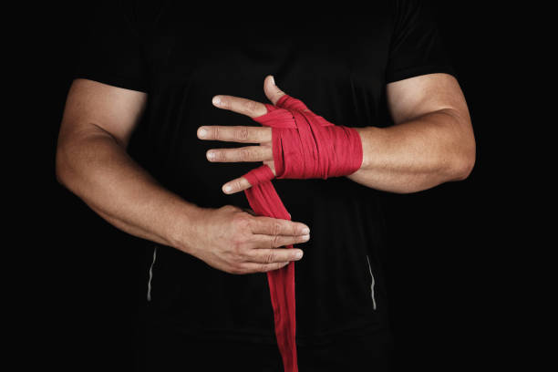 istock athlete stand in black clothes and wrap his hands in red textile elastic bandage before training 1162356281