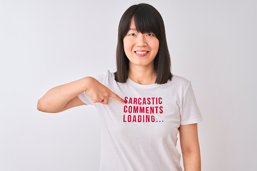 Young beautiful Chinese woman wearing fanny t-shirt over isolated white background with surprise face pointing finger to himself