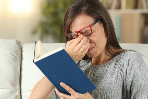 istock Woman with eyeglasses suffering eyestrain reading a book 1162358434