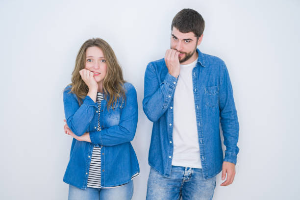 istock Young beautiful couple standing together over white isolated background looking stressed and nervous with hands on mouth biting nails. Anxiety problem. 1162360493