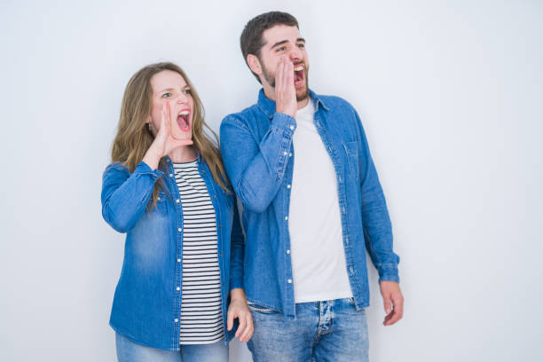 istock Young beautiful couple standing together over white isolated background shouting and screaming loud to side with hand on mouth. Communication concept. 1162360499