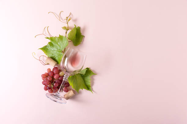 istock Single wineglass with rose wine, grape, leaves and cork lying on pink background. Wine degustation concept. Flat lay. Top view. Copy space 1162361123
