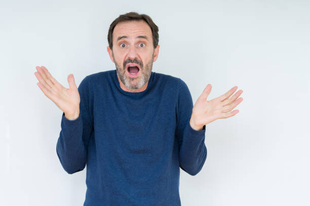 istock Elegant senior man over isolated background clueless and confused expression with arms and hands raised. Doubt concept. 1162361209