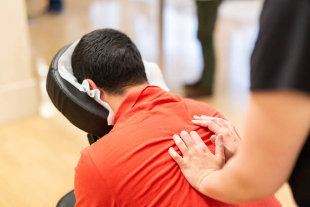 hombre recibiendo shiatsu en una silla de masaje rápido - massage therapist fotografías e imágenes de stock