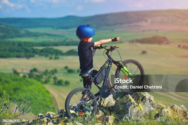Little Child Stand Next To His Mountain Bike On Mountains Edge And Looks At The Beautiful Scenery Stock Photo - Download Image Now