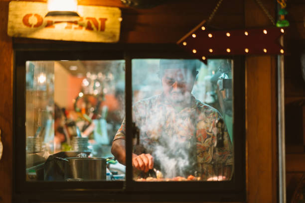 Restaurant owner cooking for customers An owner of a Japanese style pub is cooking Japanese food in the kitchen of his shop. restaurant window stock pictures, royalty-free photos & images