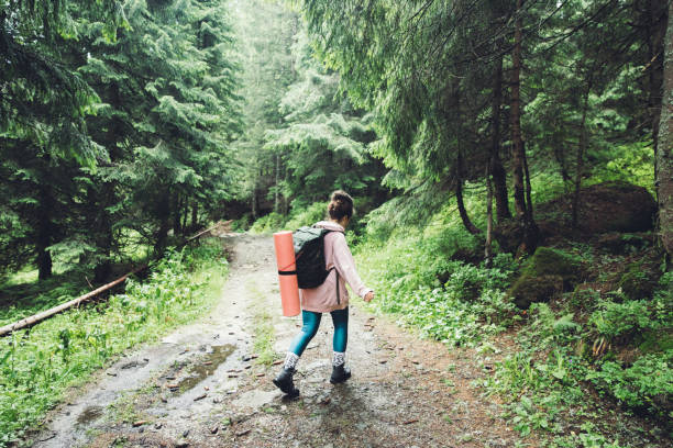 Shot of female backpacker crossing water during a hike in the forest