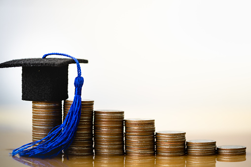 Sombrero de graduación en monedas de dinero sobre fondo blanco. photo