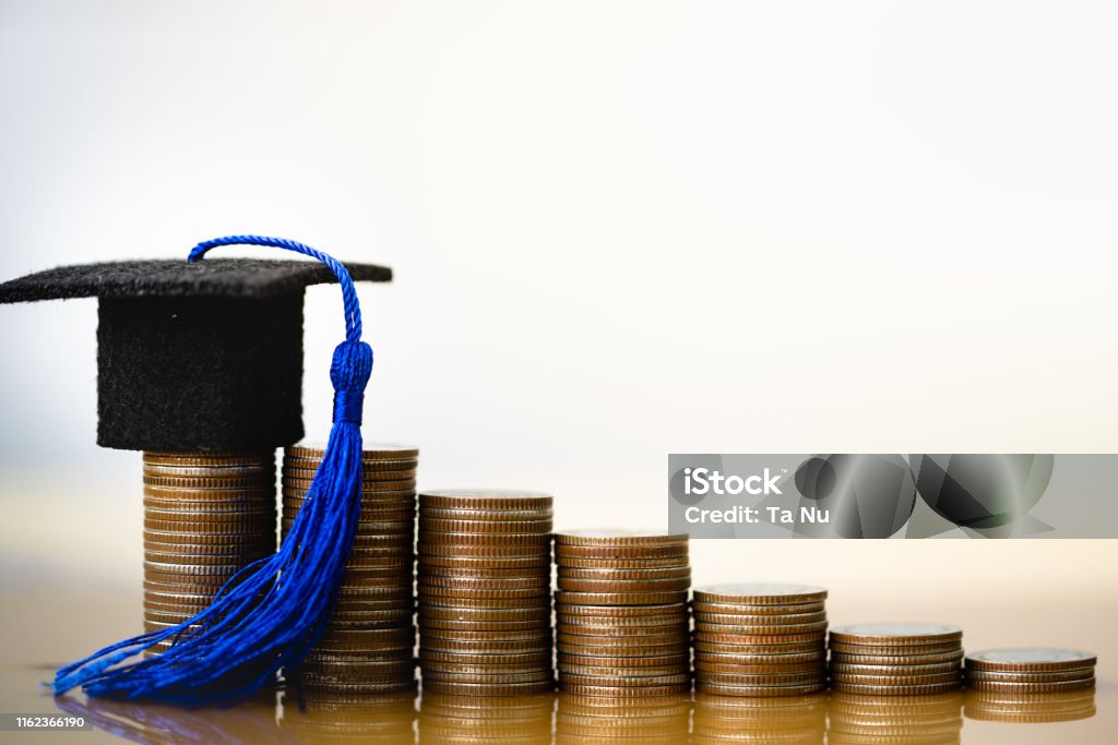 Graduation hat on coins money on white background. Graduation hat on coins money on white background. Saving money for education or scholarship concepts. Conception of education fee, education expenses, school tuition cost, graduation cap with coin. Student Loan Stock Photo