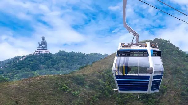 Photo of Hong Kong cable car over green mountain with Giant Buddha statue