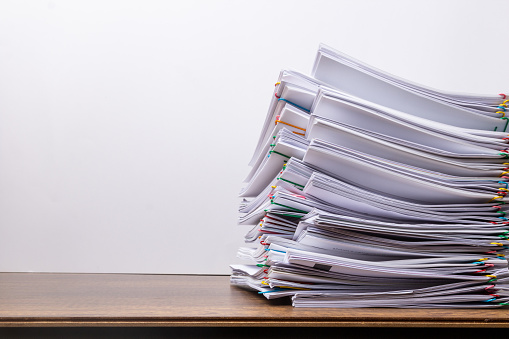 Stack of document paper with colorful paperclip place on wooden table, business concept paperless used and work overload .