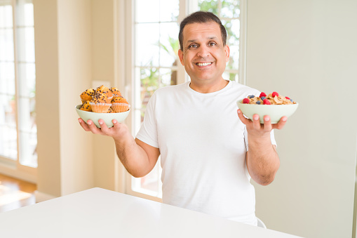Middle age arab man choosing between healthy food and junk food