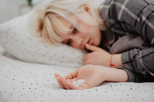 Mujer joven rubia deprimida acostada en su cama y tomando medicamentos antidepresivos. Vista superior. Problemas mentales con depresión y bulimia. photo