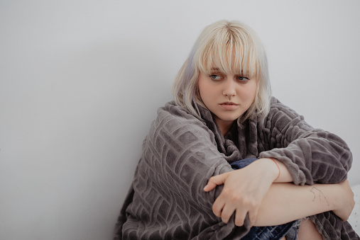 Joven rubia deprimida sentada sola en su habitación. Problemas mentales con depresión y bulimia. photo
