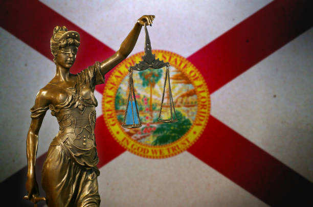 Close-up of a small bronze statuette of Lady Justice before a flag of Florida.