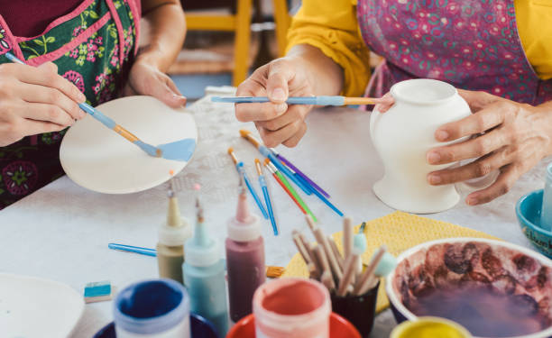 woman coloring handmade dishes using brush and color - ceramics imagens e fotografias de stock