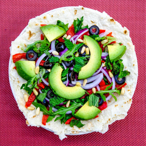 Vegetarian Avocado Salad on a Pizza Base With Red Onions, Red Peppers Mint and Black Olives
