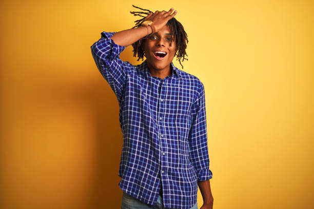 istock Afro man with dreadlocks wearing casual shirt standing over isolated yellow background surprised with hand on head for mistake, remember error. Forgot, bad memory concept. 1162387784