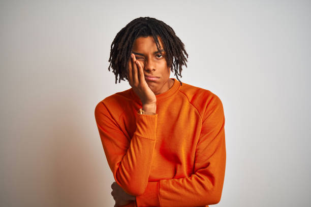istock Afro american man with dreadlocks wearing orange sweater over isolated white background thinking looking tired and bored with depression problems with crossed arms. 1162387970