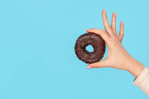 istock Chocolate glazed doughnut in female hand 1162388062