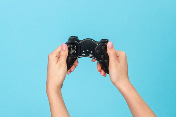 istock Woman playing with gamepad on blue background 1162388066