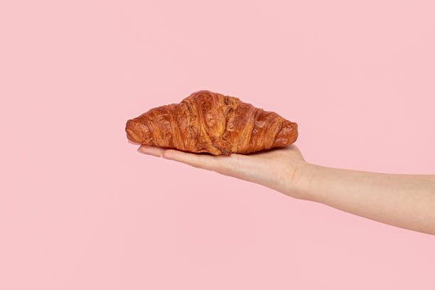 istock Crop hand presenting golden croissant 1162388103