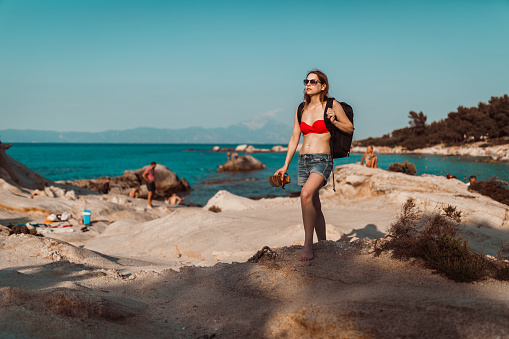 Young woman with a backpack enjoying summer vacation in Greece