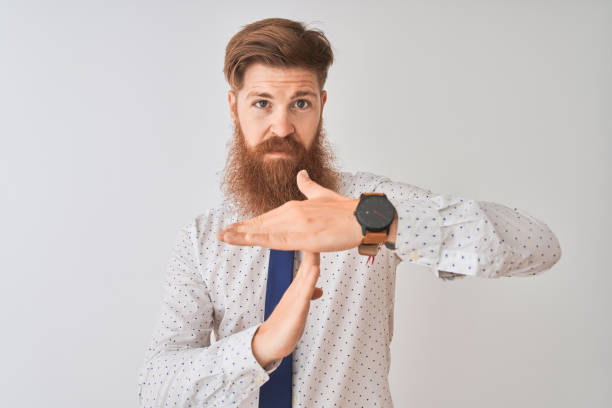 istock Young redhead irish businessman standing over isolated white background Doing time out gesture with hands, frustrated and serious face 1162389412