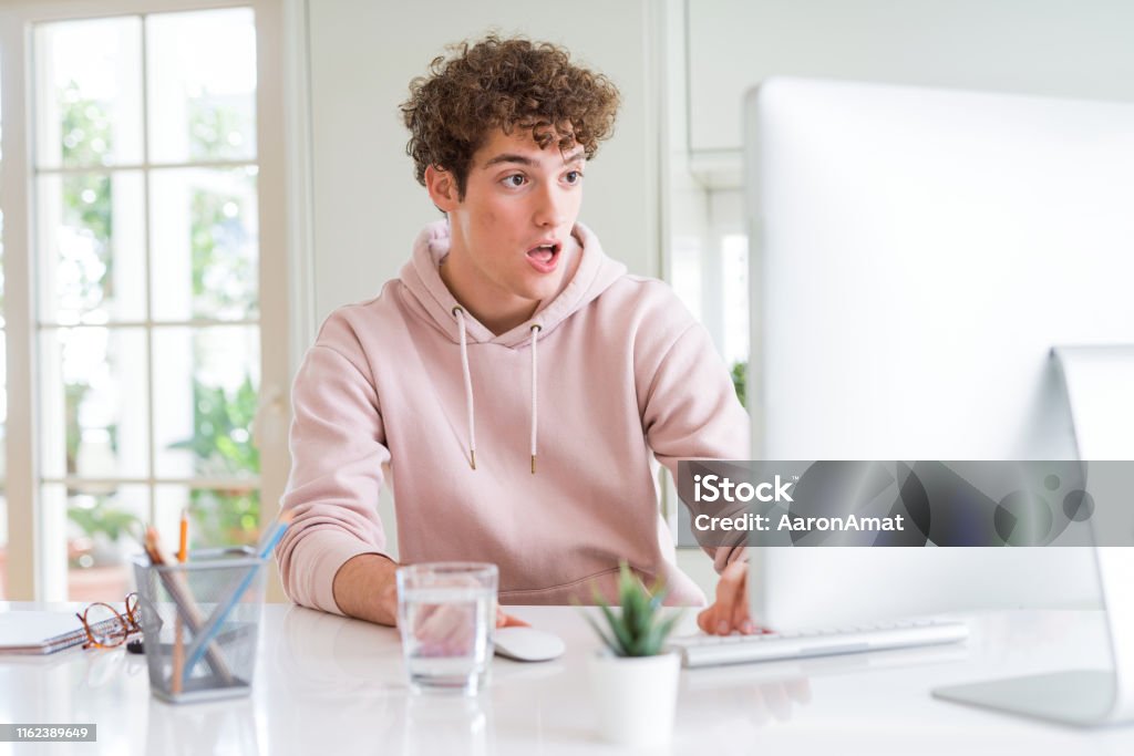 Young Student Man Using Computer Scared In Shock With A Surprise Face ...