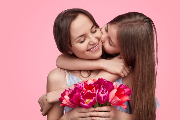 girl kissing mother with spring bouquet - mother gift imagens e fotografias de stock