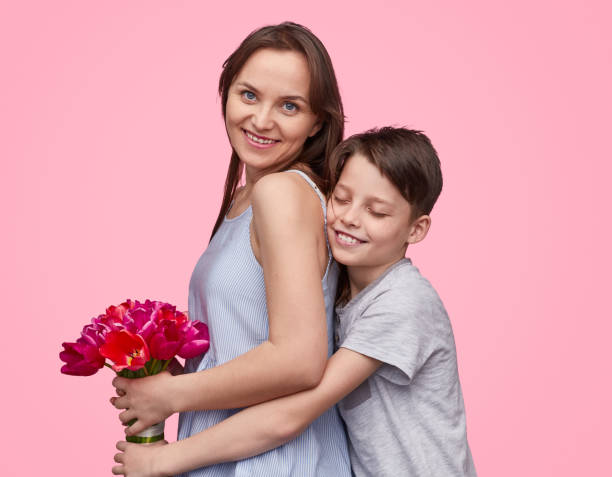 istock Son hugging and giving flowers to mother 1162390943
