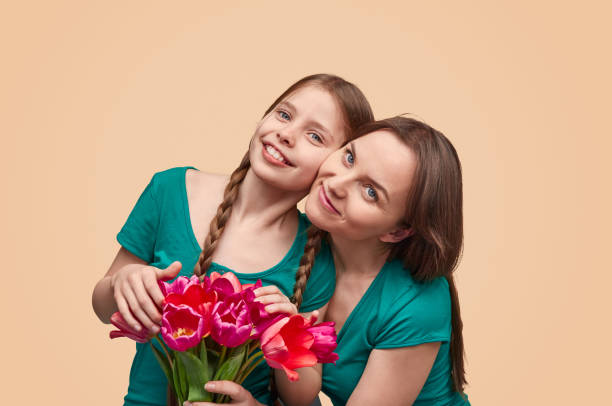 istock Mother and daughter with flowers posing for camera 1162390954