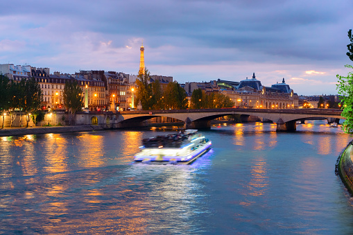 Pont Neuf and Cite island over Seine river with floating boat at night, France