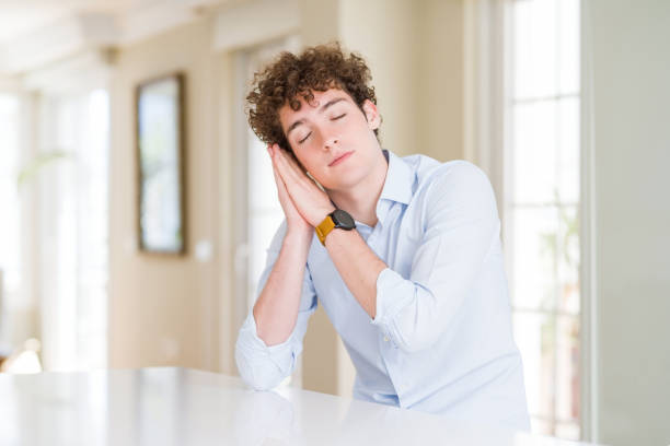 istock Young business man with curly read head sleeping tired dreaming and posing with hands together while smiling with closed eyes. 1162392690
