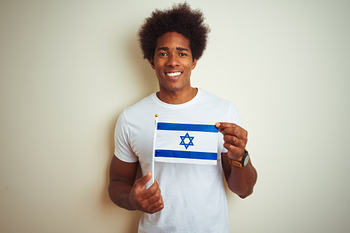 Young african american man holding Israel Israeli flag standing over isolated white background with a happy face standing and smiling with a confident smile showing teeth