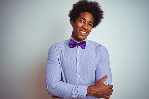 Afro business man wearing striped shirt and purple bow tie over isolated white background happy face smiling with crossed arms looking at the camera. Positive person.