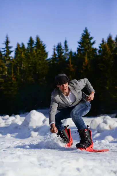 Photo of Snowboarder in casual suit riding the board