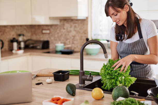istock Woman washing salad in sink. Kitchen interior. 1162400853