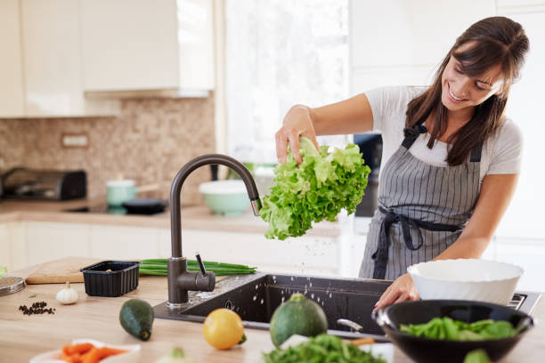 istock Woman washing salad in sink. Kitchen interior. 1162401064