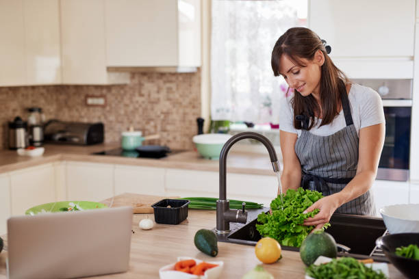 istock Woman washing salad in sink. Kitchen interior. 1162401734