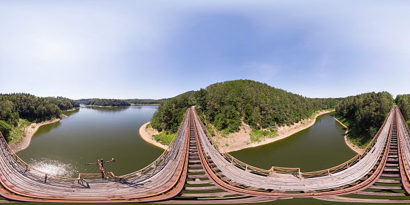 360 degrees spherical panoramic shot of an old rusty railroad bridge over the lake/river