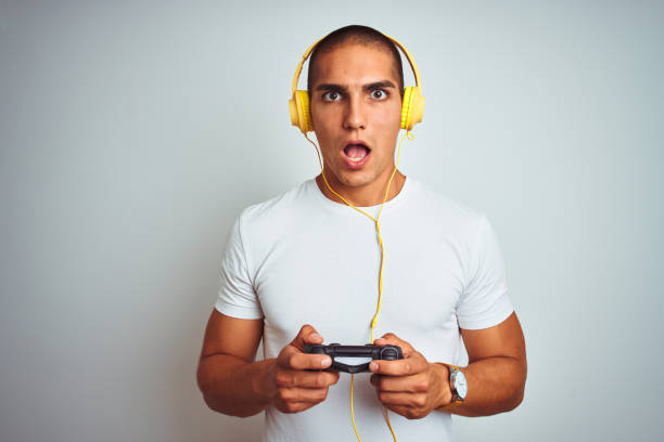istock Young handsome man playing videogames using headphones over white isolated background scared in shock with a surprise face, afraid and excited with fear expression 1162406078